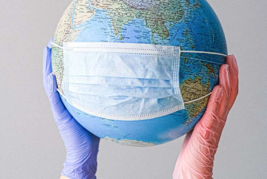 hands with latex gloves holding a globe with a face mask